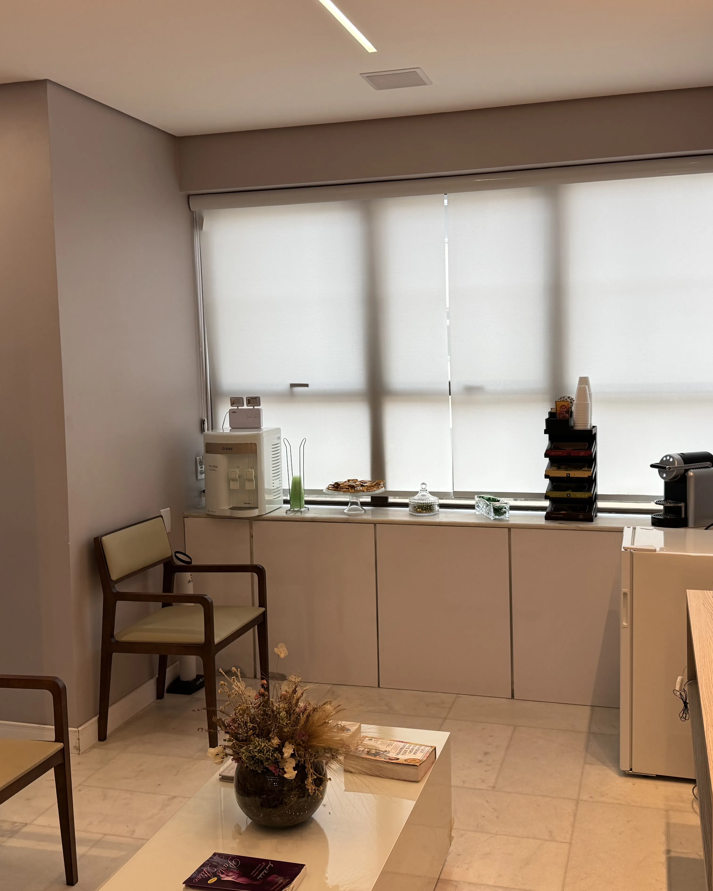 Sala de espera: janela, café, poltronas e painel de madeira