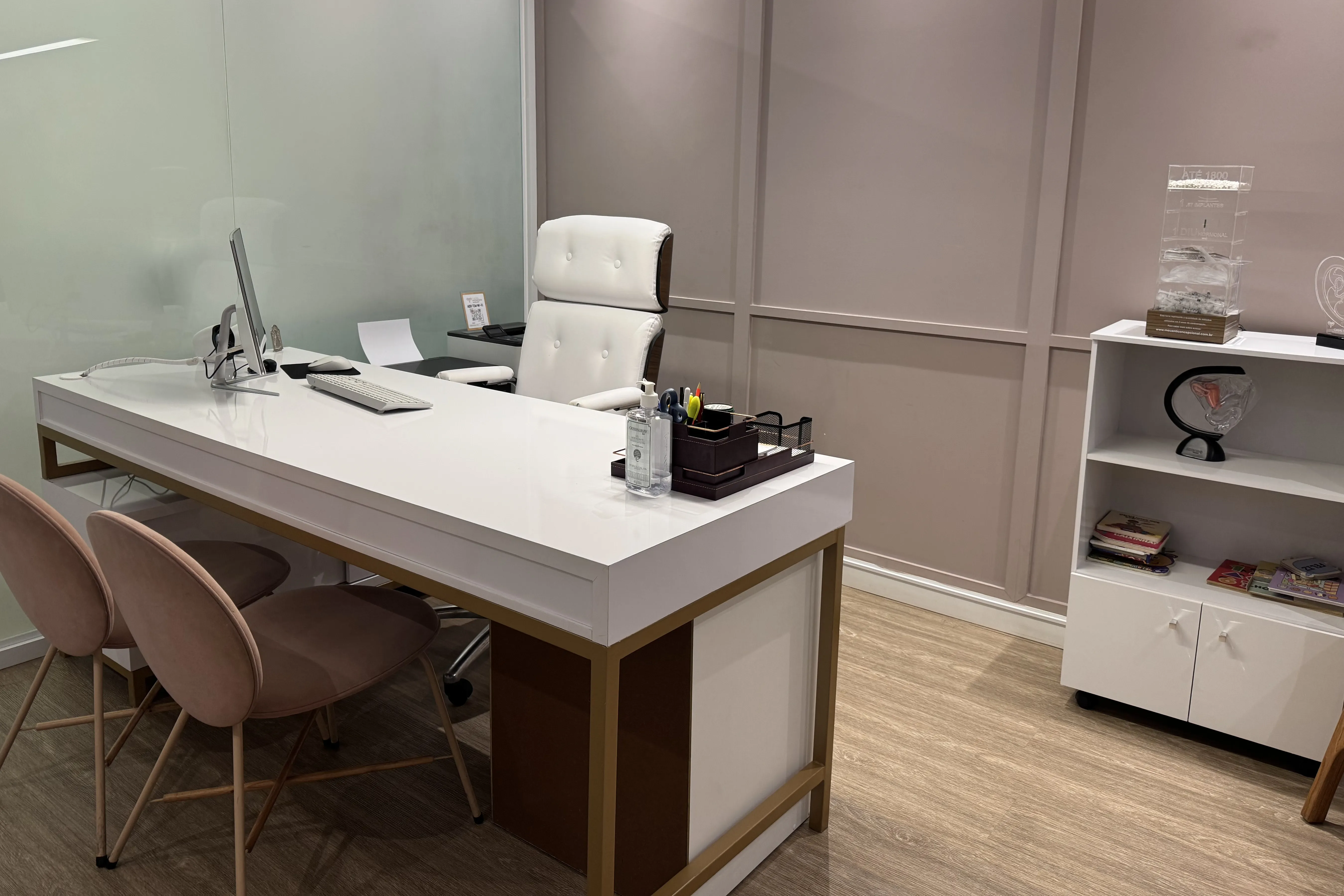 Consultório principal: boiserie rosé, mesa branca com pé dourado e cadeiras de veludo