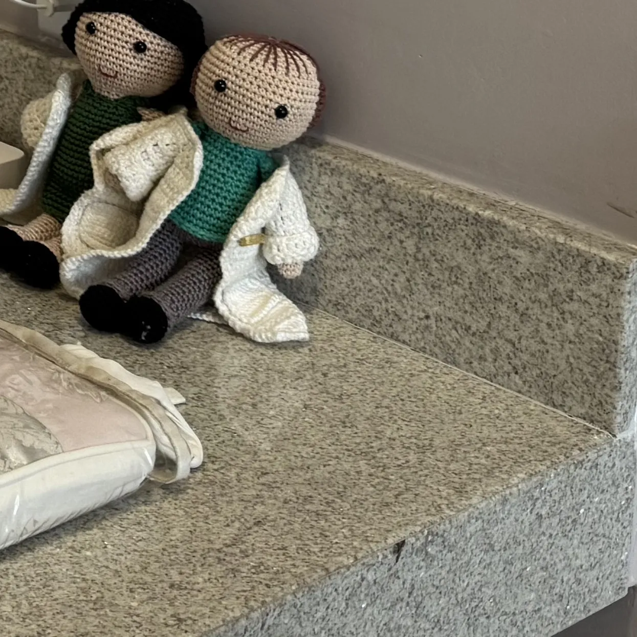 Dois bonecos de crochê de jaleco, no trocador da clínica