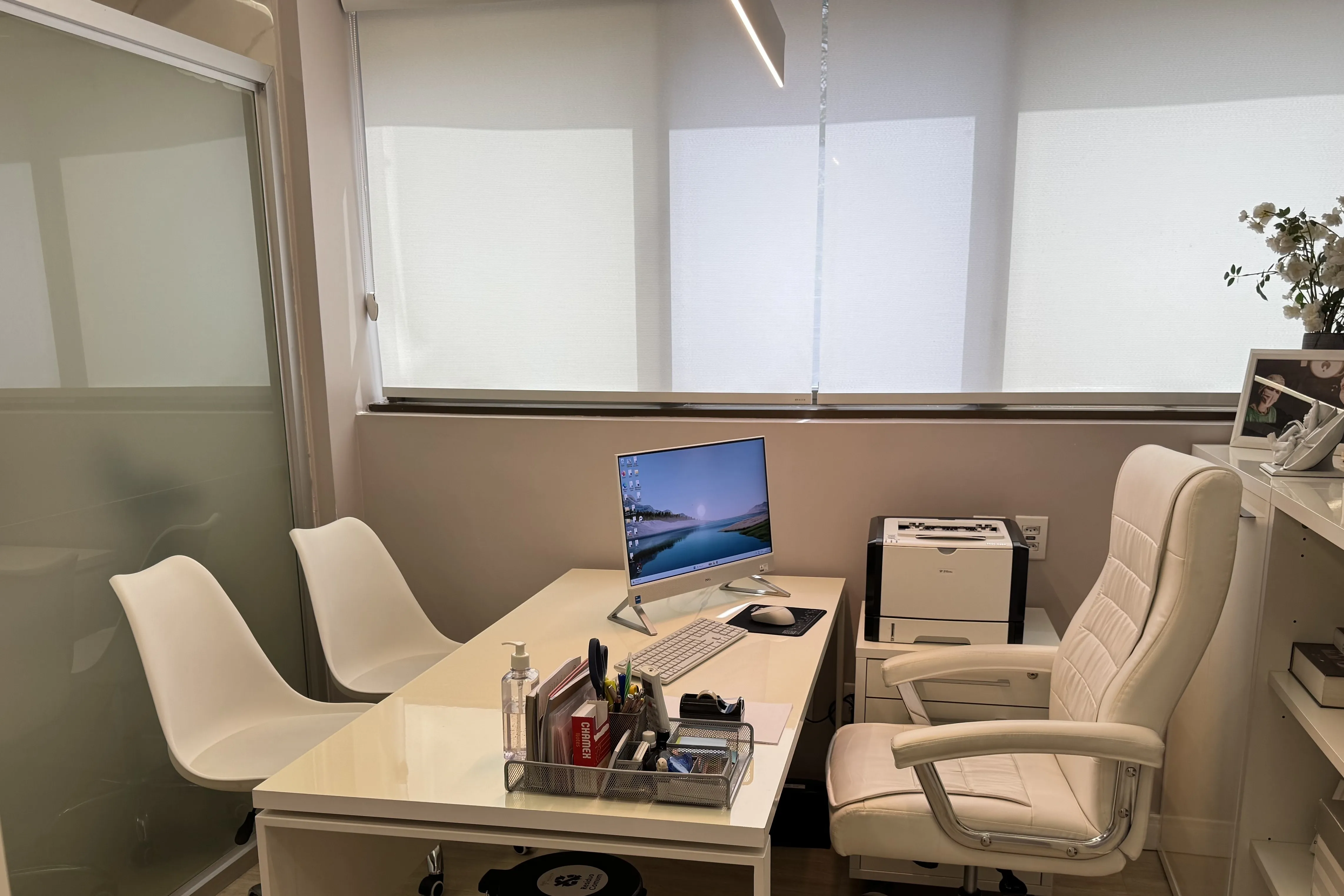 Consultório 1: mesa branca, duas cadeiras e janela com persiana